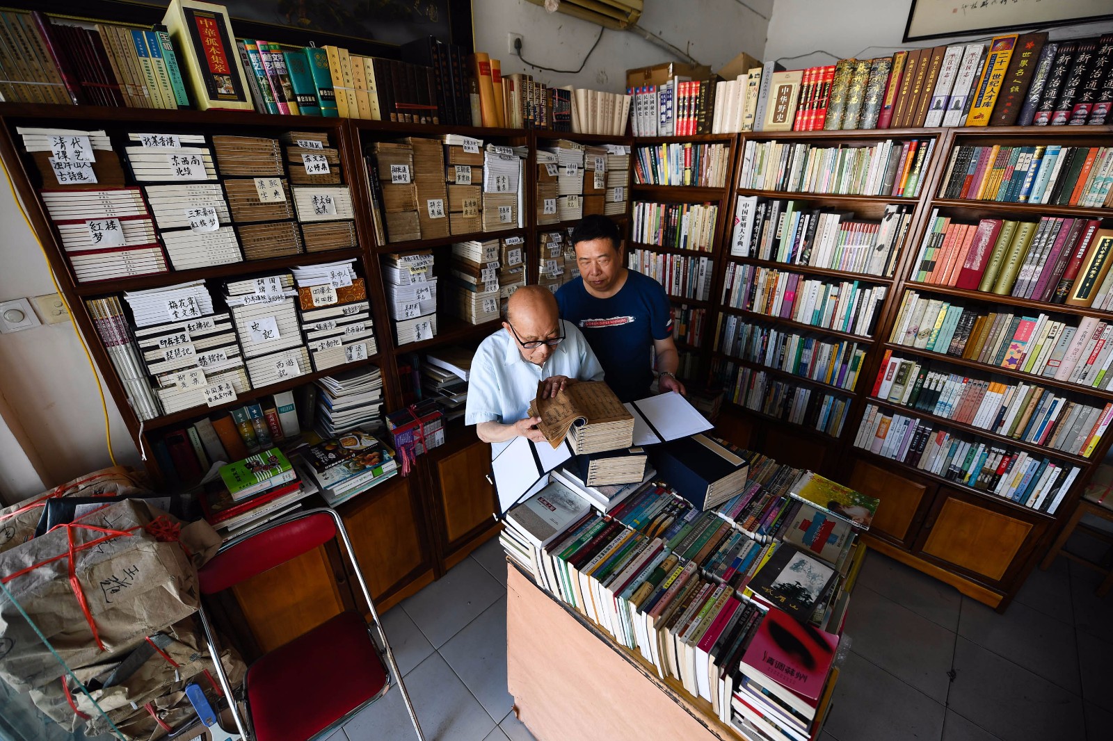    7月18日，在“文学山房”旧书店，江澄波老人和儿子江益林一起查看线装古书。 
